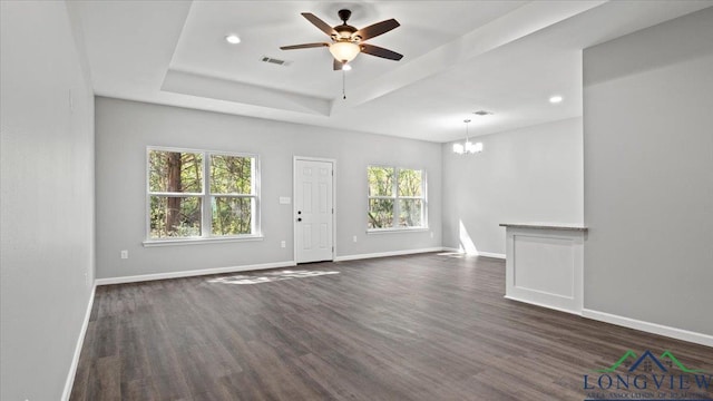 unfurnished living room featuring dark hardwood / wood-style flooring, ceiling fan with notable chandelier, and a raised ceiling