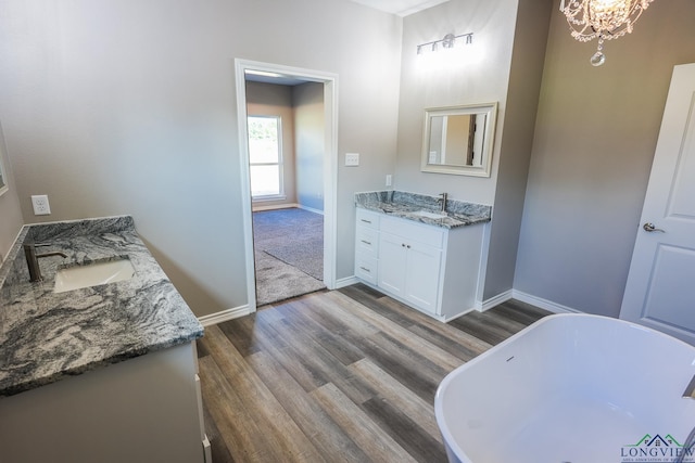 bathroom with a tub to relax in, an inviting chandelier, vanity, and hardwood / wood-style flooring