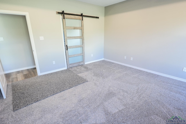 unfurnished room with carpet and a barn door