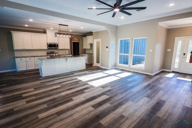 kitchen with pendant lighting, white cabinets, dark hardwood / wood-style floors, an island with sink, and stainless steel appliances