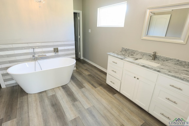 bathroom with hardwood / wood-style floors, a washtub, and vanity