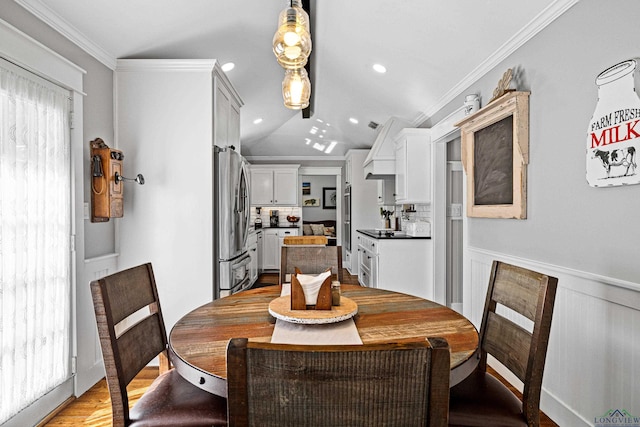 dining room featuring lofted ceiling, crown molding, and light hardwood / wood-style flooring