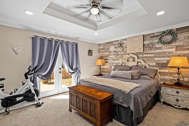 carpeted bedroom with a raised ceiling, ceiling fan, wooden walls, and crown molding