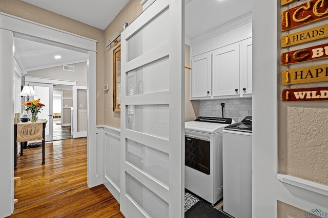 laundry room featuring cabinets, hardwood / wood-style flooring, and washer and dryer