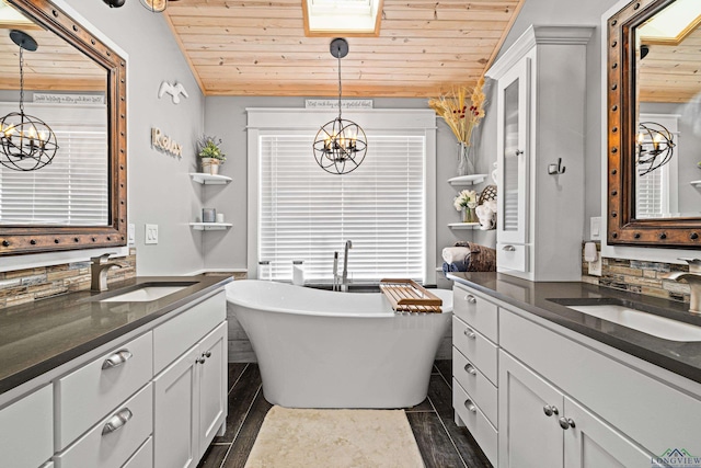 bathroom featuring vanity, wooden ceiling, an inviting chandelier, a skylight, and a tub to relax in