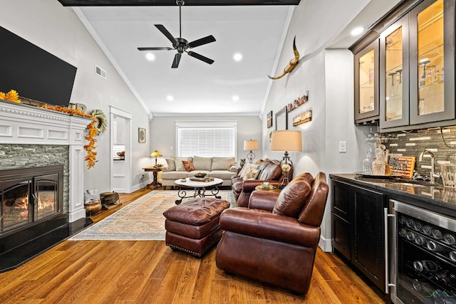 living room with wine cooler, indoor wet bar, wood-type flooring, vaulted ceiling, and ornamental molding