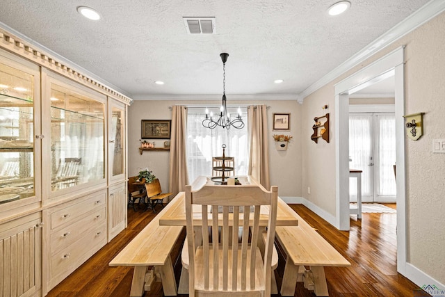 dining space featuring a chandelier, a textured ceiling, crown molding, and dark wood-type flooring