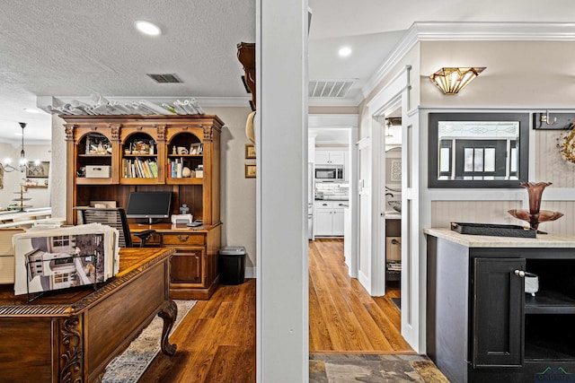 interior space featuring tasteful backsplash, a notable chandelier, crown molding, a textured ceiling, and hardwood / wood-style flooring