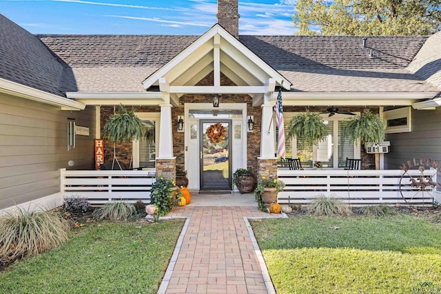 doorway to property with a porch, ceiling fan, and a lawn