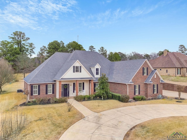 view of front of home with driveway, a front lawn, a shingled roof, and brick siding