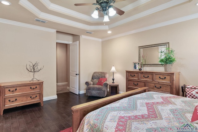 bedroom with visible vents, dark wood finished floors, baseboards, ornamental molding, and a tray ceiling