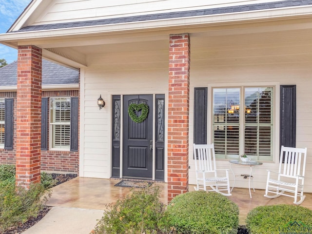 property entrance featuring covered porch and brick siding