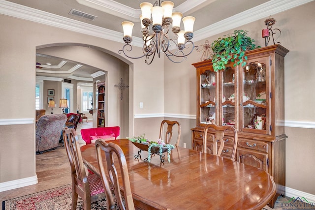 dining room featuring arched walkways, a notable chandelier, visible vents, baseboards, and crown molding