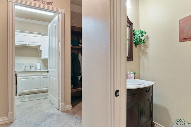 hall with ornamental molding, a sink, and baseboards