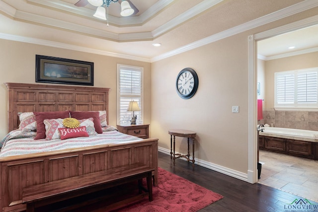 bedroom with baseboards, a raised ceiling, dark wood-type flooring, ensuite bathroom, and crown molding