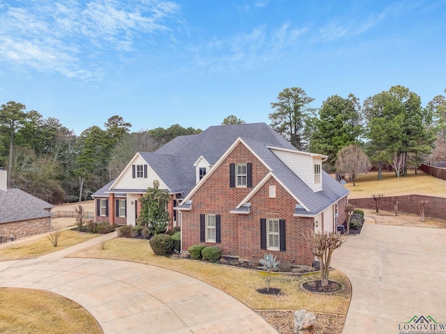 traditional-style home featuring a front yard, brick siding, and driveway