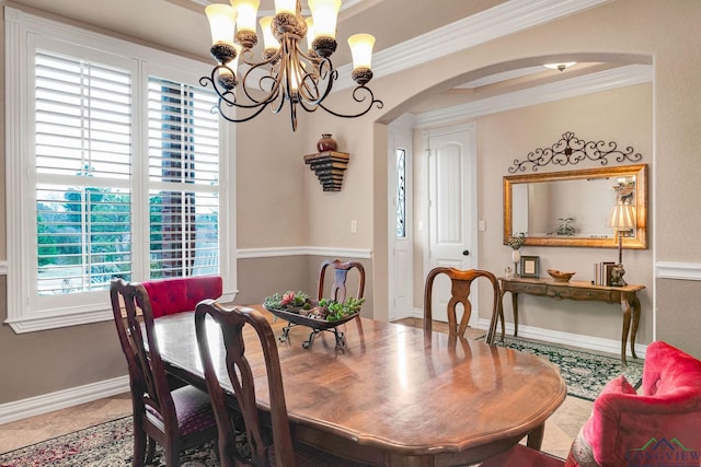 tiled dining area with a notable chandelier, baseboards, arched walkways, and crown molding