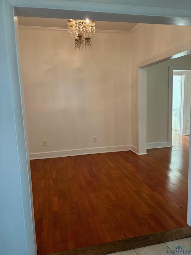 unfurnished room with wood-type flooring, crown molding, and a notable chandelier