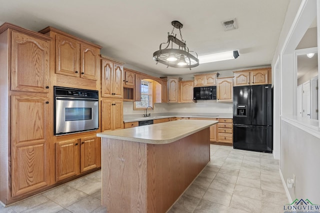 kitchen featuring decorative light fixtures, sink, light tile patterned floors, a kitchen island, and black appliances