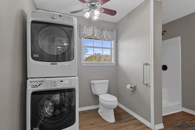 bathroom with wood-type flooring, toilet, stacked washer / drying machine, and ceiling fan