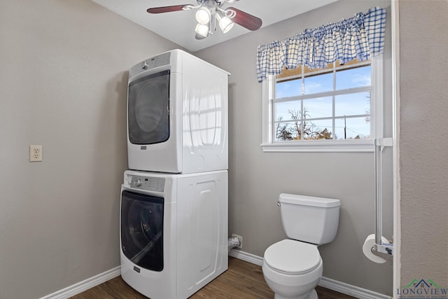 bathroom featuring toilet, stacked washer and clothes dryer, hardwood / wood-style floors, and ceiling fan