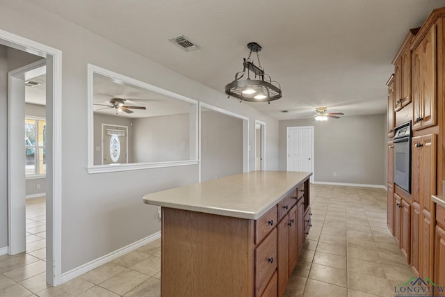 kitchen with pendant lighting, light tile patterned floors, oven, and a kitchen island