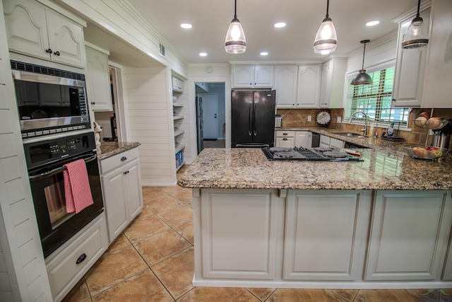 kitchen featuring light stone counters, a peninsula, a sink, black appliances, and backsplash