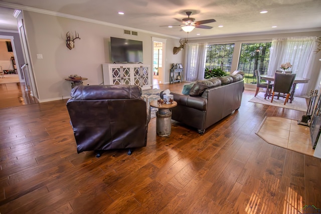 living area featuring wood-type flooring, visible vents, baseboards, and ornamental molding