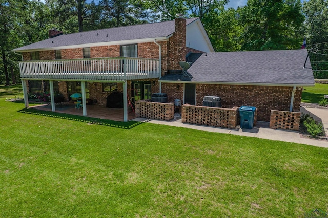 back of property with brick siding, a chimney, a shingled roof, a lawn, and a patio area