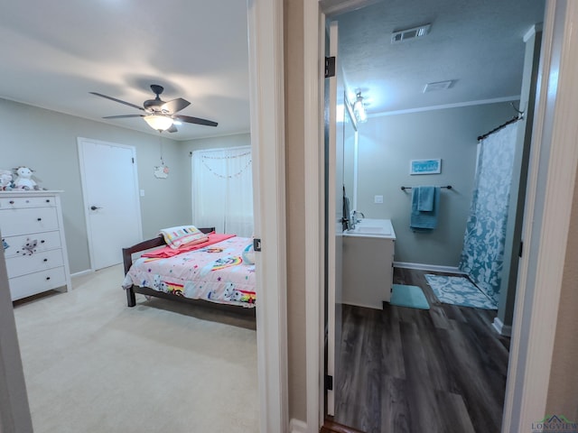 bedroom featuring baseboards, ceiling fan, wood finished floors, crown molding, and a sink