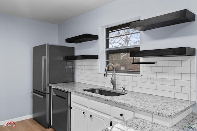 kitchen featuring decorative backsplash, appliances with stainless steel finishes, light wood-type flooring, sink, and white cabinetry