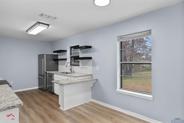 kitchen featuring decorative backsplash, stainless steel appliances, a healthy amount of sunlight, sink, and white cabinets