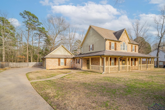 view of front of home featuring concrete driveway, brick siding, covered porch, and a front yard