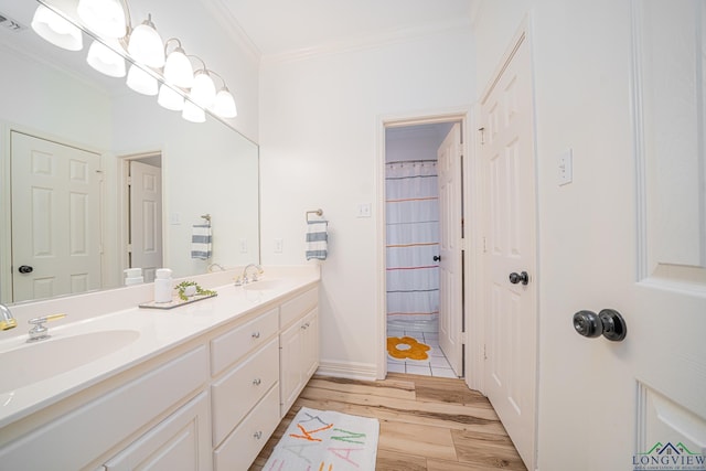 bathroom featuring visible vents, crown molding, double vanity, wood finished floors, and a sink