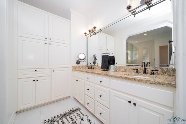 bathroom with tile patterned flooring, double vanity, ornamental molding, and a sink