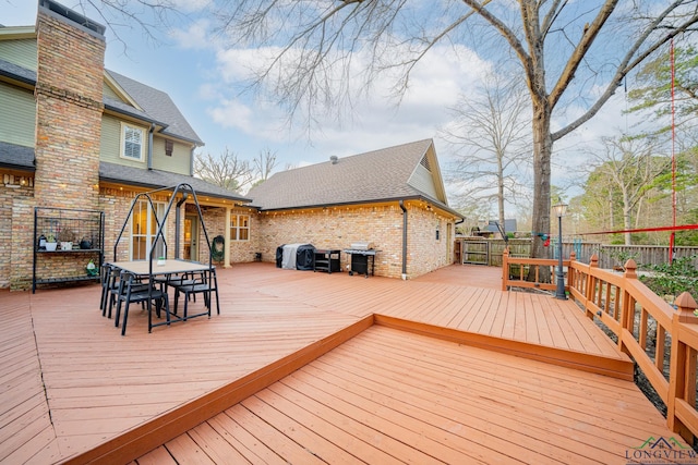 wooden terrace with outdoor dining area, fence, and a grill