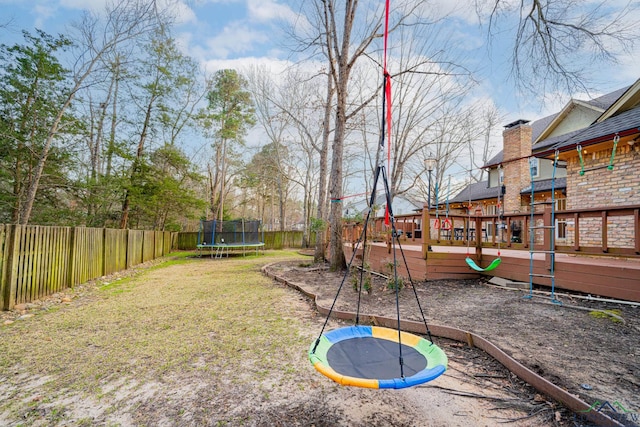 view of yard featuring a fenced backyard, a deck, and a trampoline