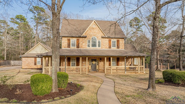 view of front of house with brick siding, covered porch, and roof with shingles