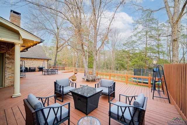 deck featuring a fenced backyard, outdoor lounge area, outdoor dining area, and a trampoline