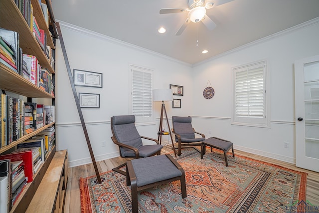 living area with ceiling fan, baseboards, wood finished floors, and ornamental molding