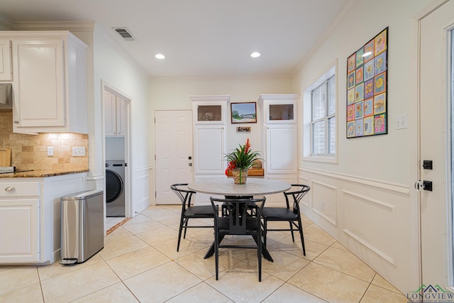 dining space featuring visible vents, washer / clothes dryer, light tile patterned flooring, and a decorative wall