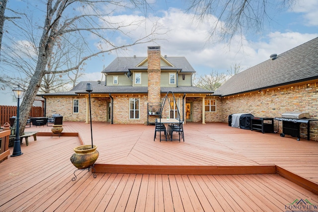 deck featuring outdoor dining space, fence, and a grill