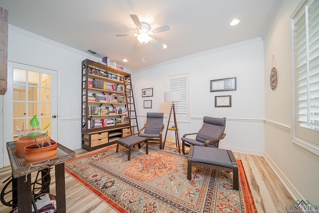 living area featuring visible vents, wood finished floors, ceiling fan, and crown molding