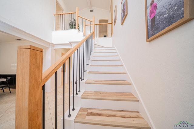 stairway featuring tile patterned flooring, beam ceiling, and high vaulted ceiling