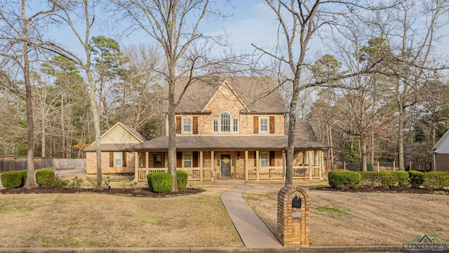 view of front of home featuring brick siding, a porch, a front yard, and fence