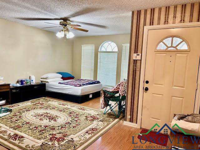 bedroom featuring ceiling fan, a textured ceiling, and light wood-type flooring