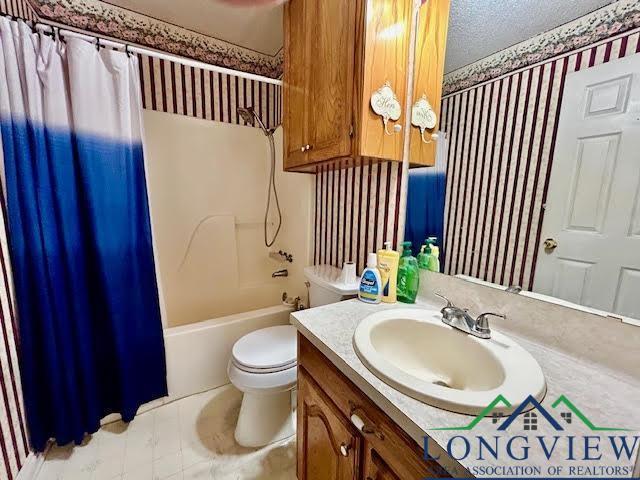 full bathroom featuring shower / tub combo with curtain, vanity, a textured ceiling, and toilet