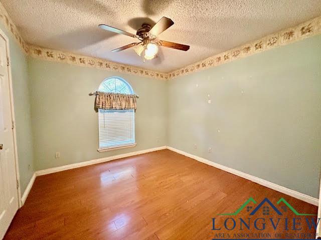 spare room with a textured ceiling, hardwood / wood-style flooring, and ceiling fan