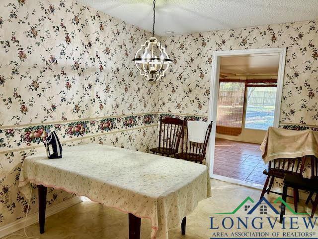 tiled dining room featuring a textured ceiling and an inviting chandelier