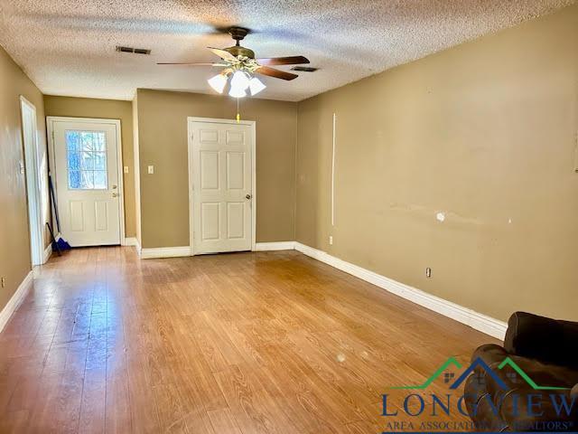 interior space featuring ceiling fan, wood-type flooring, and a textured ceiling